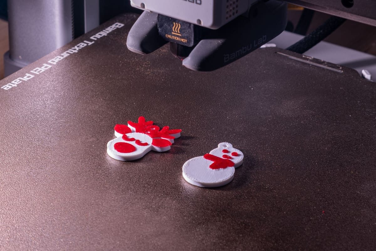 Adornos festivos en rojo y blanco recién impresos sobre la cama de la impresora 3D.